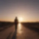 Silhouette of a person walking towards a bright horizon